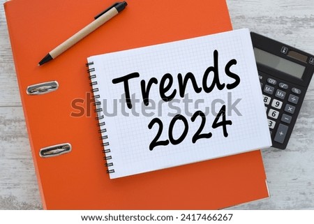TRENDS 2024 notepad on orange folder. text on the table