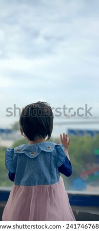 Baby Girl wearing dress and looking the view from window. picture focus on the baby back