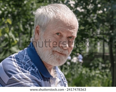 Portrait of an elderly gray-haired man on the blurred background of a house under construction . Portrait of a gray-haired bearded man in a T-shirt.
