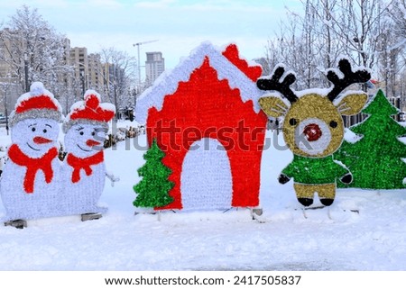 Festive toys stand on the city street in winter. Funny houses, snowmen and deer. Dnipro city