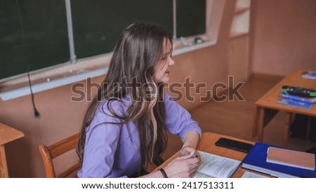 A young female student leads the class in the role of teacher.