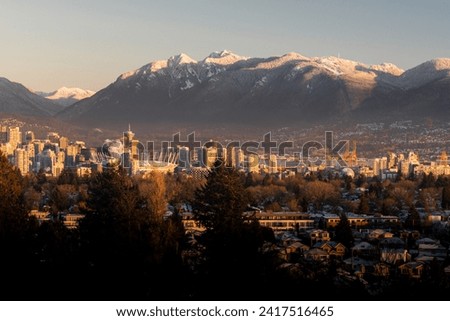 A beautiful morning view of Vancouver cityscape from Queen Elizabeth Park in British Columbia, Canada. Enjoy the snowy city view, mountains, and park during the golden hour at sunrise in winter.  