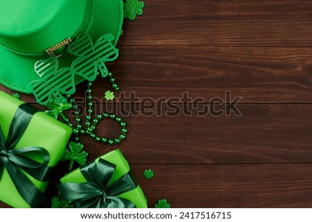 Emerald enchantment: Celebrate St. Patrick's Day with presents. Top view photo of gift boxes, leprechaun hat, party glasses, trefoils, beads on wooden background with promo area
