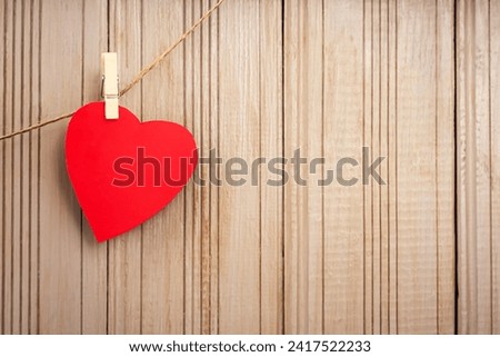 Red paper heart hanging on clothespins on wooden background. Love concept. Copy space