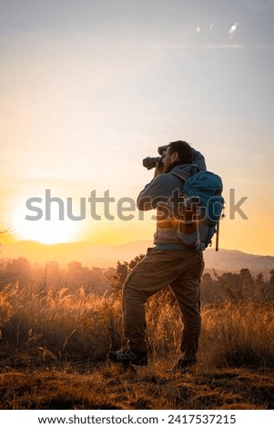 The photographer, camera in hand and backpack on his back, celebrates the encounter with the sun over the majestic mountains