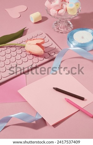 Empty gift card decorated with crayons, a roll of blue ribbon and pink keyboard. A glass tray featured many marshmallows. Copy space on gift card for text adding