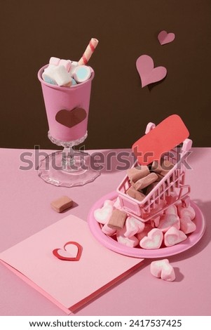 Many holiday items decorated on pink surface for banner design with a cup, a trolley and a dish of marshmallows displayed with a gift card. Celebration background concept