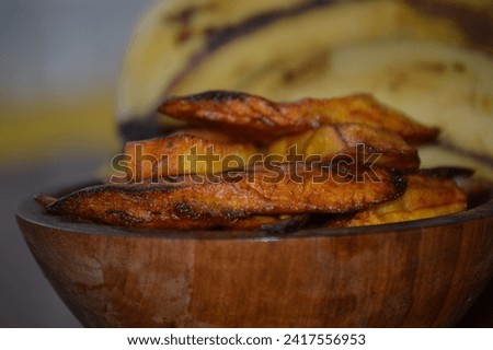 Delicious banana fried on the plate on a rustic wooden board. Typical dish of Brazilian cuisine made with sliced earth banana and crispy fries, crispy fried nanana recipe Royalty-Free Stock Photo #2417556953