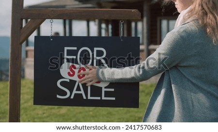 Female real state agent puts sold sticker on for sale sign and goes to buyers. Young family with kids talks about their new modern house and looks views around. Residential property on sale concept.