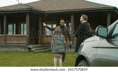 African American real estate agent meets and greets couple with kids near selling property. Realtor invites family to show house. People visit potential new home. For sale sign on lawn.