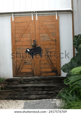 ฺBrown wooden door on sheep farm.Sign with picture of sheep on wooden wall. Farm animal