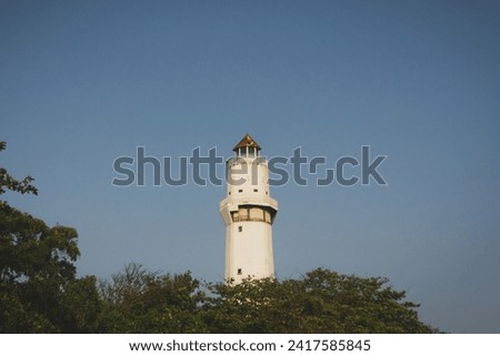 lighthouse tower from below with a background of clear skies and leaves
