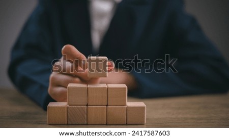Businesswomen stack blank wooden cubes on the table with copy space, empty wooden cubes for input wording, and an infographic icon.