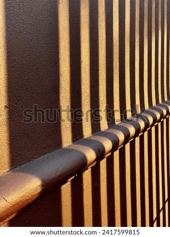 Striped style sunbeams and wall shadows on a yellow orange vintage style building facade   