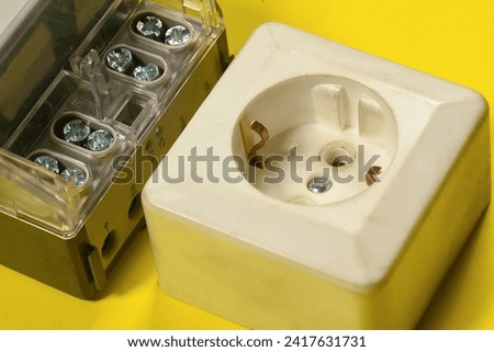 Electricity meter and electric plug close up on the yellow top view background.
