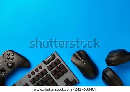 Computer keyboard and joystick on blue background top view