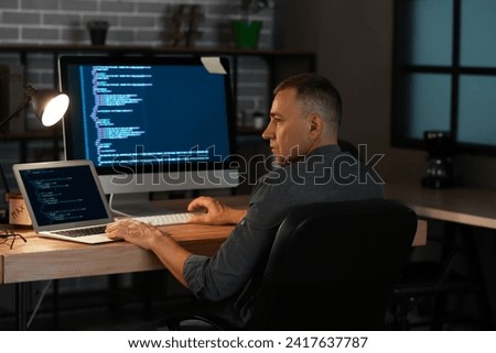 Mature male programmer working in office at night