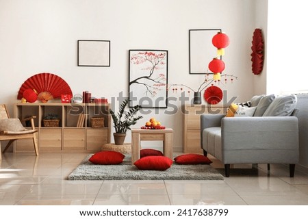 Coffee table with tangerines and cushions on floor in festive living room. Chinese New Year celebration Royalty-Free Stock Photo #2417638799