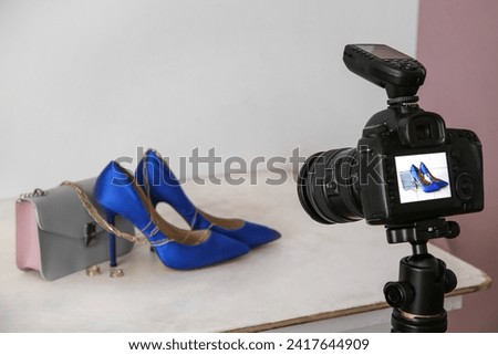 Fashionable shoes, purse and jewellery on display of professional photo camera in studio