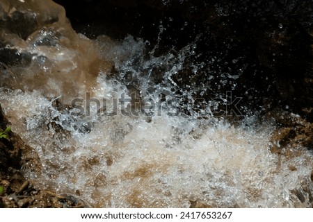 Photo taken with fast shutter speed of wild flowing water through a rocky gully with splashing water droplets
