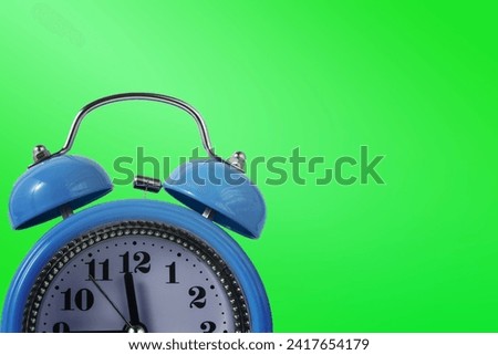 Alarm clock over green. Time concept. Blue alarm clock morning time. Blue alarm clock with copy space...Blue alarm clock with copy space on a green background.