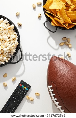 Popcorn and chips with a rugby ball on a light background