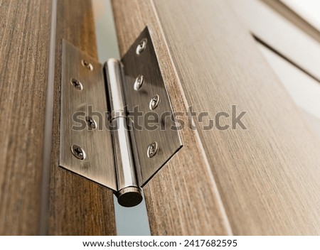 Close-up of a door hinge on a wooden interior door with glass inserts. Royalty-Free Stock Photo #2417682595