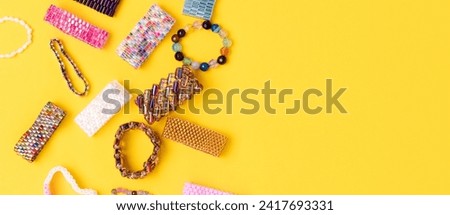 Banner with handmade beaded rings scattered on a yellow background. 