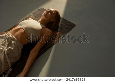 Young woman practicing corpse asana in yoga studio. Savasana pose. Relaxation concept Royalty-Free Stock Photo #2417695923