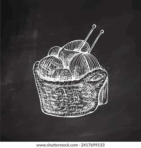 Hand-drawn sketch of basket with balls of yarn, wool and knitting needles on chalkboard background. Knitwear, handmade, knitting equipment concept in vintage doodle style. Engraving style.