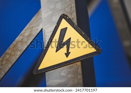 Close-up of a yellow Danger sign on a high-voltage line pole.