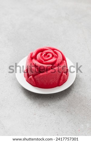 Vegan Strawberry ice cream portioned dessert in the shape of a red rose. On a plate. Light grey background. Close-up