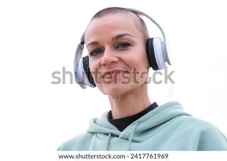  Close-up smiling sporty woman with headphones looking at the camera outdoors.