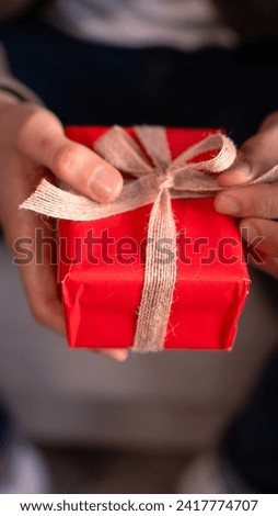 Vertical close-up Man's hands opening a Valentine's gift with a bow.