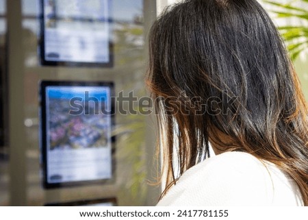 Woman looking at house listings in a real estate window.