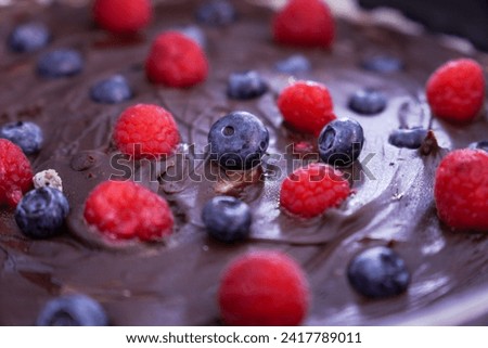 Raspberries and blueberries on chocolate cake. Fruit decoration on homemade cake.