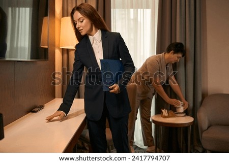 Housekeeping manager supervising maid performance during room cleaning procedure Royalty-Free Stock Photo #2417794707