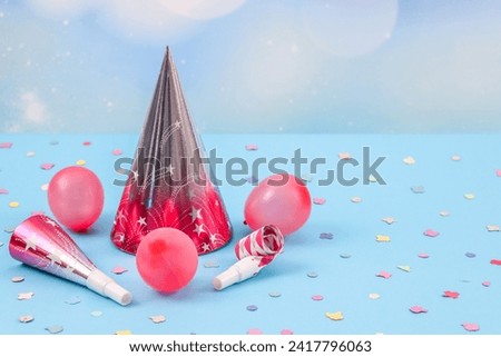 Pink cone hats,balloons,confetti and birthday whistles on a blue background.