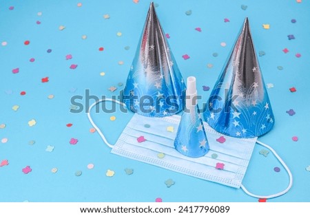 Two blue cone birthday hats, confetti and a whistle on a blue background.