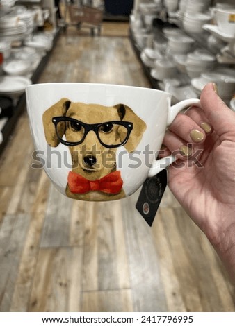 A woman holding a mug with a dachshund wearing glasses and a bow tie on it.