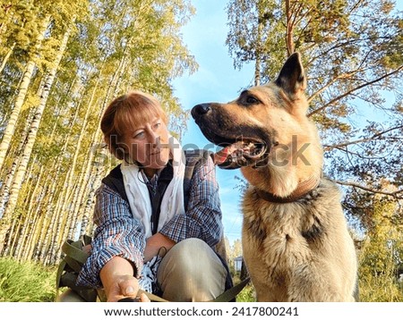 Adult girl with shepherd dog taking selfies in forest. Middle aged woman and big shepherd dog on nature. Friendship, love, communication, fun, hugs Royalty-Free Stock Photo #2417800241