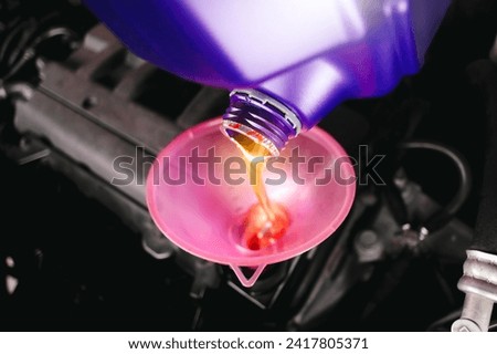 Engine oil poured into a funnel in the engine oil filler of the car engine , Car maintenance service concept Royalty-Free Stock Photo #2417805371
