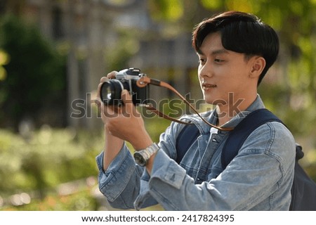 A handsome Young Asian traveler man taking a picture of a beautiful Thai Temple with his camera, Thailand traveling and Solo traveler concept.