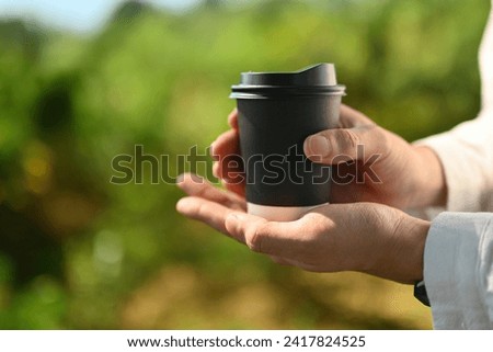 Close up image of unrecognizable's hands holding a takeaway coffee cup, Outdoors.