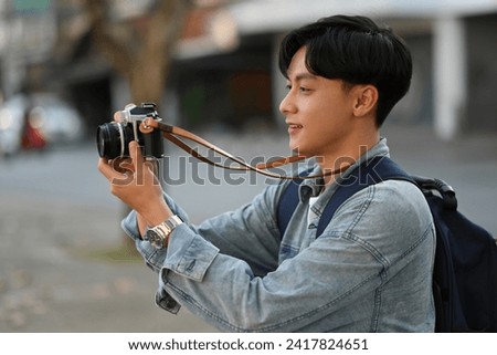 A handsome Young Asian traveler man taking a picture of a city view with his camera, Solo traveler concept.