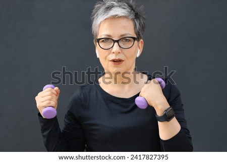 A fit and active mature woman exercising with dumbbells outdoors, embodying a healthy lifestyle in her senior years.