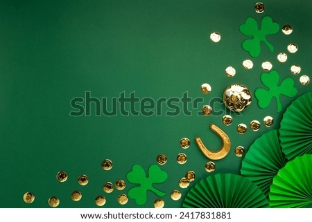 St. Patrick's Day leprechaun hat, gold coins and shamrocks on green background. Irish traditional holiday concept. Top view, copy space.
