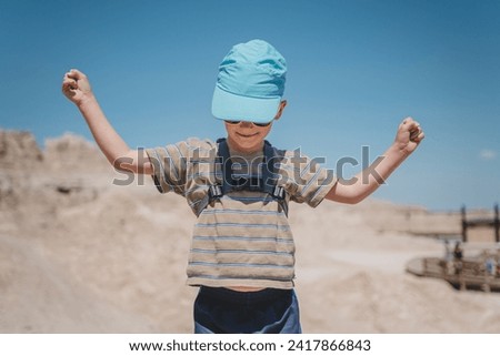 Young boy raising his hands amidst the rock formations of Badlan