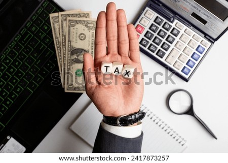 Tax word written on white office background with laptop, US dollar, diary and calculator on it.