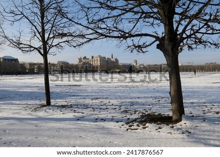 Saint-Germain-en-Laye castle between trees seen from the park covered by snow